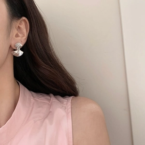 Elegant fan-shaped silver drop earrings with textured finish and pearl accent on model