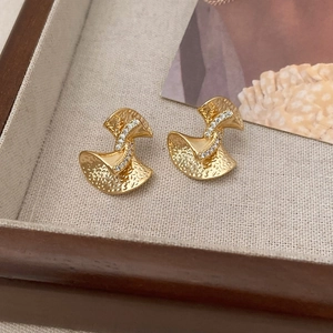 Detail view of gold bow earrings with textured hammer finish and pave set zircon stones