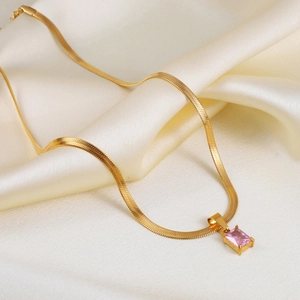 Gold snake chain necklace featuring a rectangular pink zircon pendant on white silk fabric
