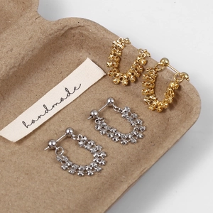 Detail of gold and silver handmade chain earrings on textured vintage tray