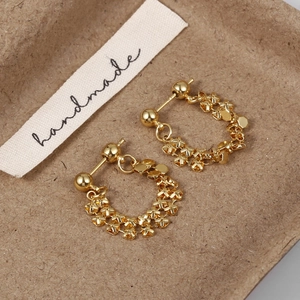 Detailed close-up of golden handmade earrings with geometric facets on brown tray