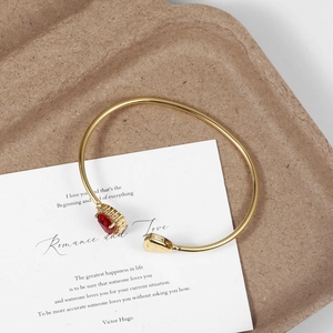 Minimalist 18K gold-plated cuff bracelet featuring a red pear-shaped gemstone and crystal halo