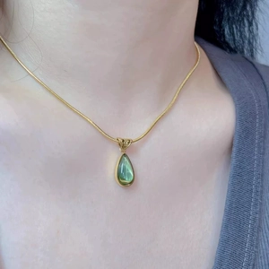 French vintage necklace featuring golden snake chain with green teardrop gem pendant
