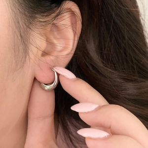 Macro shot of polished silver chunky hoop earrings worn by a model for a chic look