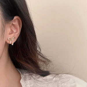 Elegante Schleifenohrringe mit funkelnden Kristallen und Perlen am Damenmodel