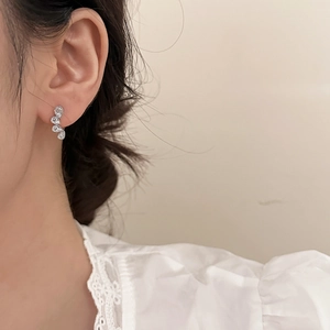 Close-up of elegant tear-drop crystal earrings in a silver finish worn by a model