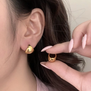 Minimalist thick gold hoop earrings with polished metal finish worn by model