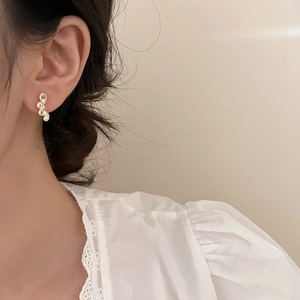 Detail showing four sparkling teardrop crystals set in curved gold-tone stud earrings