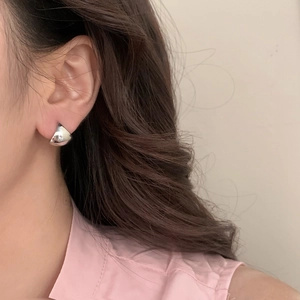 Minimalist silver geometric saddle stud earrings with a polished mirror finish on model
