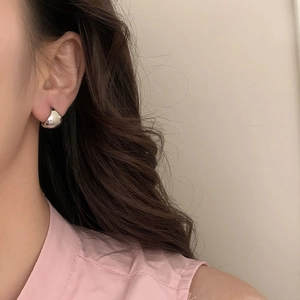 Close-up of minimalist silver hoop earring with polished mirror finish on model ear