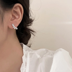 Elegant silver teardrop earrings with four curved cubic zirconia crystals on model