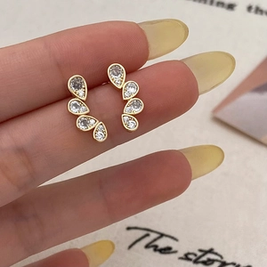 Detailed close-up of teardrop zirconia stud earrings with gold plating on curved metal