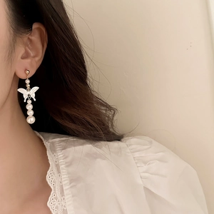 Elegant gold butterfly earrings with mother of pearl and pearls shown on a model