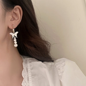 Elegant butterfly pearl drop earrings with mother of pearl and gold finish on female model