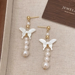 Detail of gold-plated butterfly earrings with white shell wings and gradient pearls