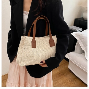 Detailed view of straw handbag with woven herringbone pattern and brown leather handles