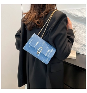 Detailed shot of denim crossbody bag with fringe edges and gold chain strap