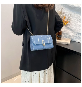 Detail of blue denim crossbody bag featuring a vintage u-shaped golden lock and chain