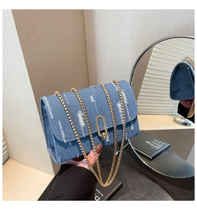 Detail of blue denim chain bag featuring distressed texture and gold oval metal lock