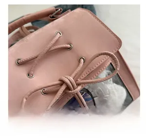 Close-up of pink crossbody bag with metal eyelets and decorative bow tie detail