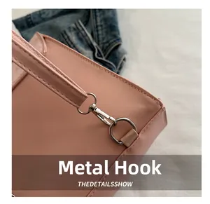 Close-up of silver metal hook and leather stitching on pink commuter crossbody bag