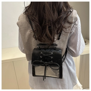 Detail of cute black Ita bag with bow and transparent window worn as a crossbody bag
