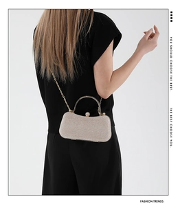 Model wearing champagne sequin evening bag with gold chain and metal handle