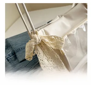Detail of cream messenger bag showing lace bow decoration and clear window feature