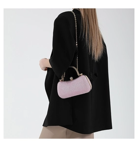Pink glitter evening clutch bag with gold handle shown worn as a crossbody bag