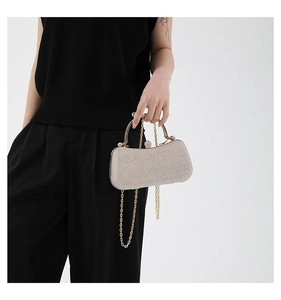 Detail of glitter evening clutch bag with crystal lock and gold chain strap held by model