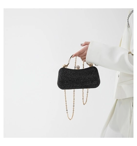 Detail of black glitter clutch bag with gold handle and sparkling rhinestone lock