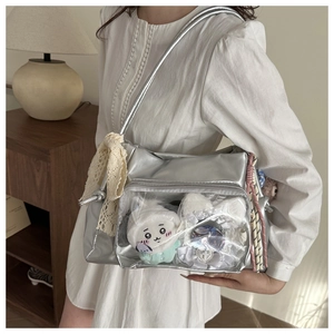 Detail of silver ita bag with clear window showing plush toys and lace bow decoration
