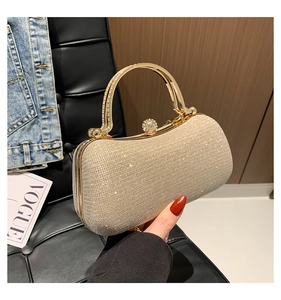 Detail of champagne gold evening clutch with glitter texture and rhinestone metal handle
