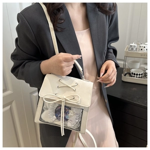 Close-up of white crossbody ita bag featuring clear window with ribbons and bows decoration
