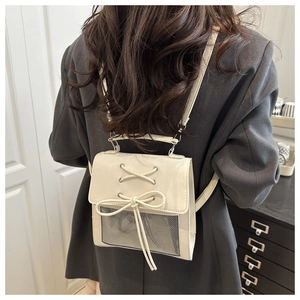 Detail of cream backpack featuring ribbon bow and clear window display for dolls