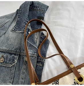 Detail of jacquard fabric tote with brown leather handle and gold metal rivets
