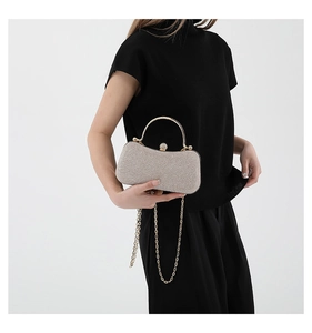 Close-up of champagne gold glitter evening clutch with rhinestone clasp and chain strap