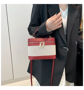 Detail of red leather and cream canvas contrast handbag with gold double metal zippers