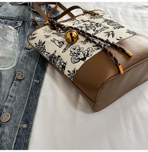 Detail of Chinese landscape print on canvas tote bag with brown leather base and bell