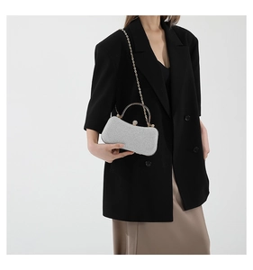 Detail of silver sequin evening bag featuring gold semicircular metal handle and chain
