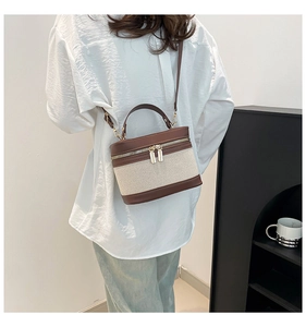 Detailed side view of vintage canvas box bag with brown leather trim and dual gold zippers