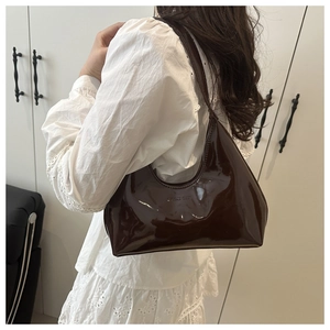Detail of high-gloss dark brown patent leather Hobo bag with embossed logo on shoulder strap