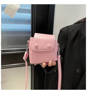 Detail of pink mini crossbody bag with large double buttons and adjustable strap