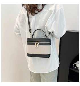 Detailed view of canvas bucket bag with black leather trim worn on a model