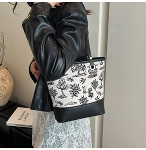 Detail of canvas bucket bag with Chinese embroidery and black leather base trim