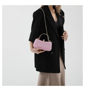 Pink glitter evening bag with gold circular handle and delicate chain strap shown on model