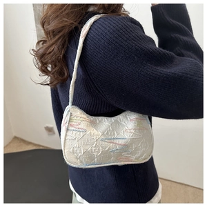 Detail of white textured fabric shoulder bag with colorful wave embroidery and relief pattern
