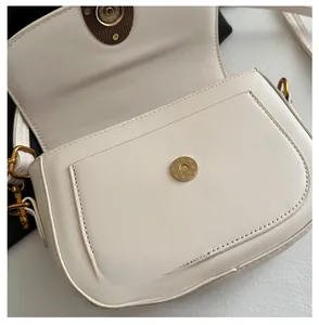 Gros plan détaillé du fermoir magnétique doré vintage et de la texture cuir du sac crème