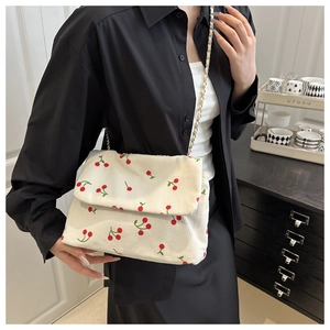 Détail du cabas en velours côtelé blanc avec imprimé cerise et chaîne dorée sur mannequin