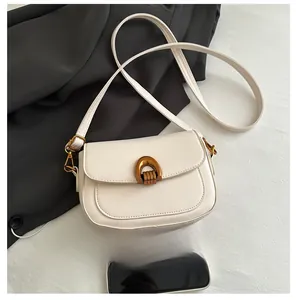 Détail du sac selle en similicuir blanc crème avec boucle en U en bronze vintage